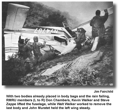 With two bodies already placed in body bags and the rain failing, RMRU members (L to R) Don Chambers, Kevin Walker and Steve Zappe lifted the fuselage, while Walt Walker worked to remove the last body and John Muratet held the left wing steady. (photo by Jim Fairchild)