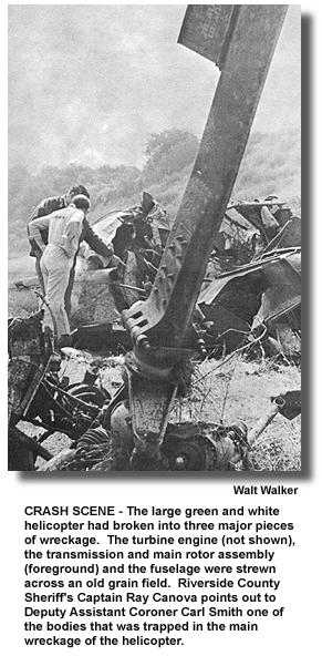 CRASH SCENE - The large green and white helicopter had broken into three major pieces of wreckage. The turbine engine (not shown), the transmission and main rotor assembly (foreground) and the fuselage were strewn across an old grain field. Riverside County Sheriff's Captain Ray Canova points out to Deputy Assistant Coroner Carl Smith one of the bodies that was trapped in the main wreckage of the helicopter. (photo by Walt Walker)