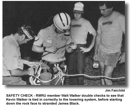 SAFETY CHECK - RMRU member Walt Walker double checks to see that Kevin Walker is tied in correctly to the lowering system, before starting down the rock face to stranded James Black. (photo by Jim Fairchild)