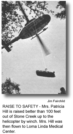 RAISE TO SAFETY - Mrs. Patricia Hill is raised better than 100 feet out of Stone Creek up to the helicopter by winch. Mrs. Hill was then flown to Loma Linda Medical Center. (photo by Jim Fairchild)