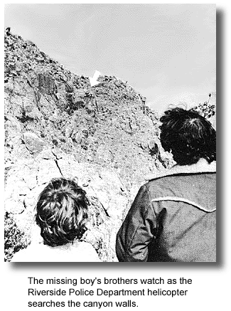 The missing boy's brothers watch as the Riverside Police Department helicopter searches the canyon walls.