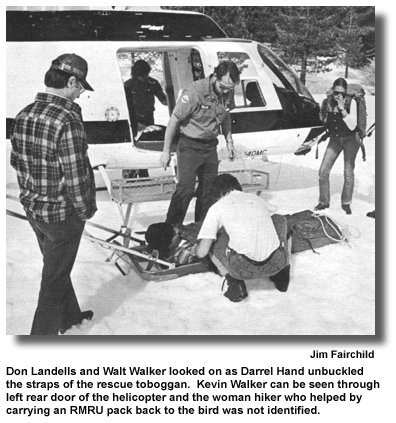 Don Landells and Walt Walker looked on as Darrel Hand unbuckled the straps of the rescue toboggan. Kevin Walker can be seen through left rear door of the helicopter and the woman hiker who helped by carrying an RMRU pack back to the bird was not identified. (photo Jim Fairchild)