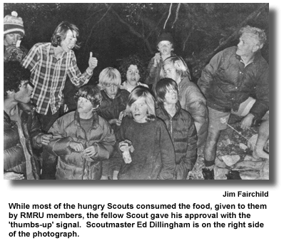 While most of the hungry Scouts consumed the food, given to them by RMRU members, the fellow Scout gave his approval with the thumbs-up signal. Scoutmaster Ed Dillingham is on the right side of the photograph. (photo by Jim Fairchild)