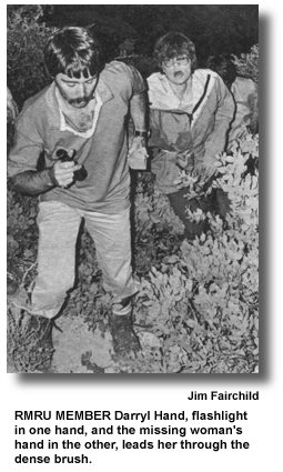 RMRU MEMBER Darryl Hand, flashlight in one hand, and the missing woman's hand in the other, leads her through the dense brush. (photo by Jim Fairchild)