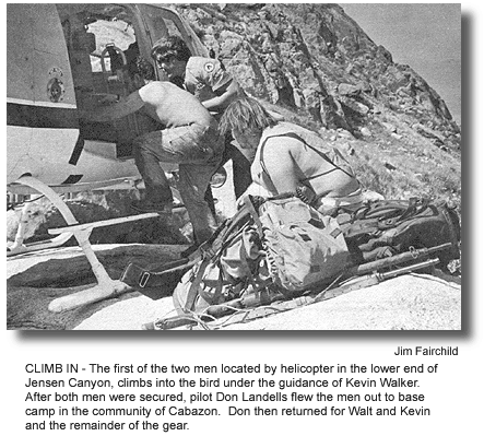CLIMB IN - The first of the two men located by helicopter in the lower end of Jensen Canyon, climbs into the bird under the guidance of Kevin Walker. After both men were secured, pilot Don Landells flew the men out to base camp in the community of Cabazon. Don then returned for Walt and Kevin and the remainder of the gear. (photo by Jim Fairchild)
