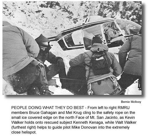 PEOPLE DOING WHAT THEY DO BEST - From left to right RMRU members Bruce Gahagan and Mel Krug cling to the safety rope on the small ice covered edge on the north Face of Mt. San Jacinto, as Kevin Walker holds onto rescued subject Kenneth Kenaga, while Walt Walker (furthest right) helps to guide pilot Mike Donovan into the extremely close helispot. (photo by Bernie McIlvoy)