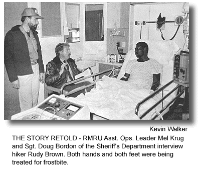 THE STORY RETOLD - RMRU Asst. Ops. Leader Mel Krug and Sgt. Doug Bordon of the Sheriff's Department interview hiker Rudy Brown. Both hands and both feet were being treated for frostbite. (photo by Kevin Walker)