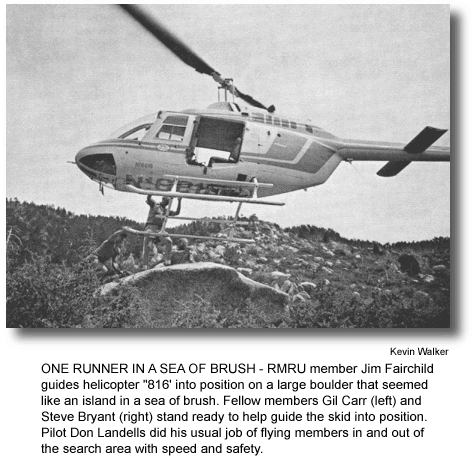 ONE RUNNER IN A SEA OF BRUSH - RMRU member Jim Fairchild guides helicopter "816' into position on a large boulder that seemed like an island in a sea of brush. Fellow members Gil Carr (left) and Steve Bryant (right) stand ready to help guide the skid into position. Pilot Don Landells did his usual job of flying members in and out of the search area with speed and safety. (photo by Kevin Walker)